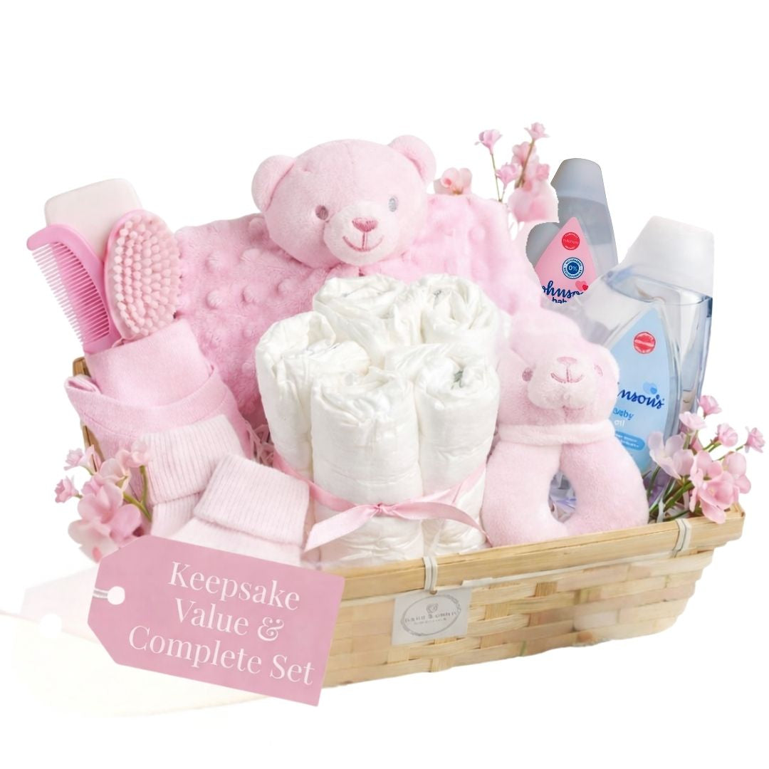 Baby girl gift hamper with teddy bear and newborn essentials in keepsake basket